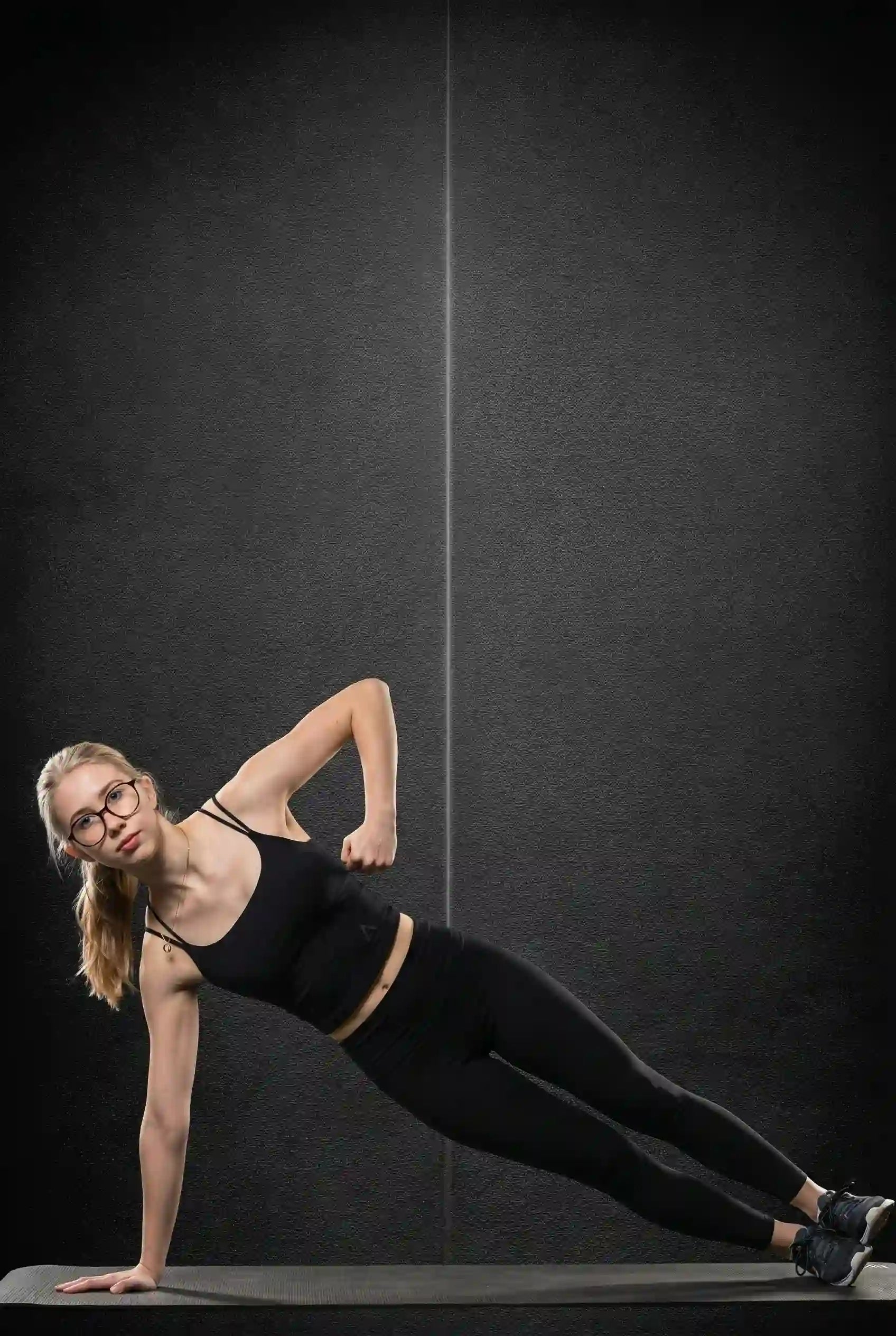 Femme en brassière noire ASCENT effectuant une fente avant dans un décor sombre, montrant maintien et confort du Women’s Luxe Bra. 